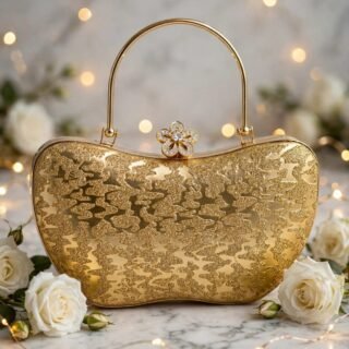 Gold glitter evening clutch with crystal flower clasp and metal top handle on a marble table