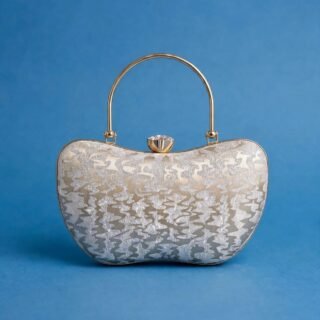 Silver glitter evening clutch with crystal clasp and gold metal top handle on a blue background