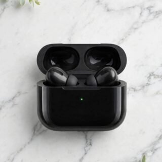 Black wireless earbuds in open glossy black charging case with green LED light on white marble background